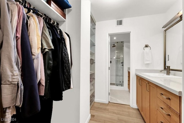 bathroom featuring visible vents, a stall shower, vanity, wood finished floors, and baseboards