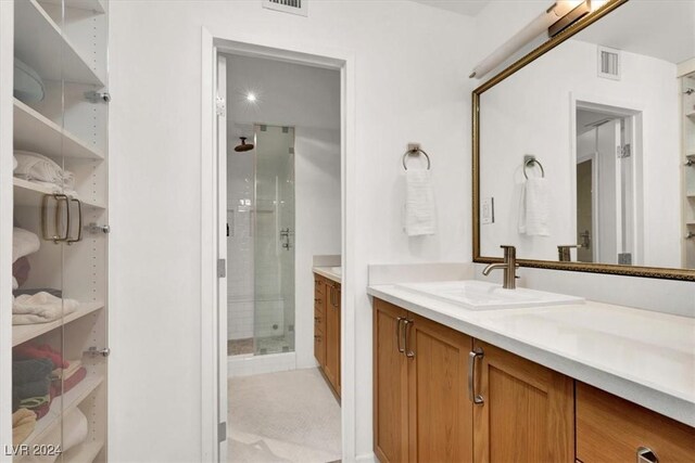 bathroom featuring a shower with shower door and vanity