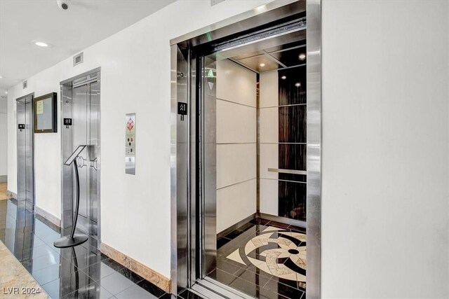 corridor featuring tile patterned flooring and elevator