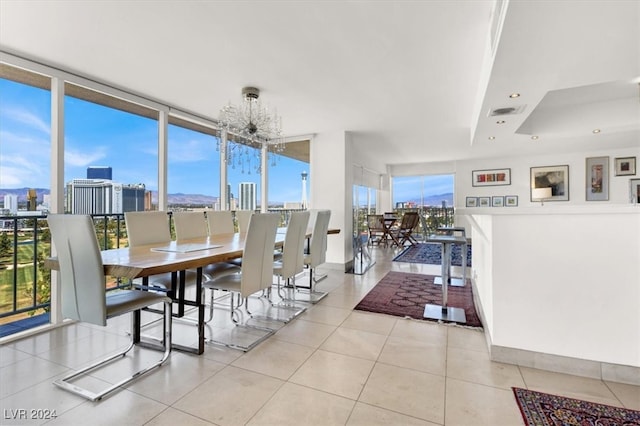 dining area with light tile patterned floors, a raised ceiling, floor to ceiling windows, and a chandelier