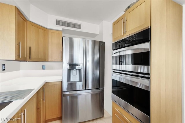 kitchen featuring light tile patterned flooring, visible vents, light countertops, appliances with stainless steel finishes, and light brown cabinetry