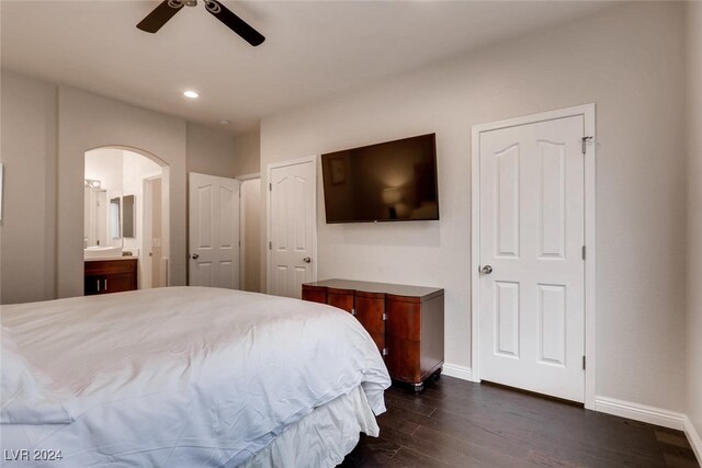 bedroom with ceiling fan, connected bathroom, dark hardwood / wood-style flooring, and two closets