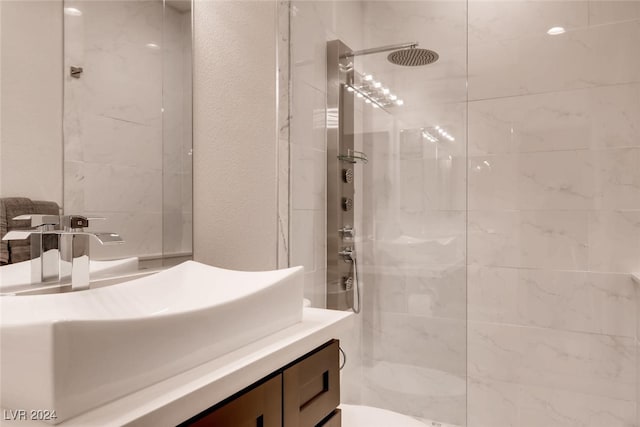 full bath with a textured wall, walk in shower, and vanity