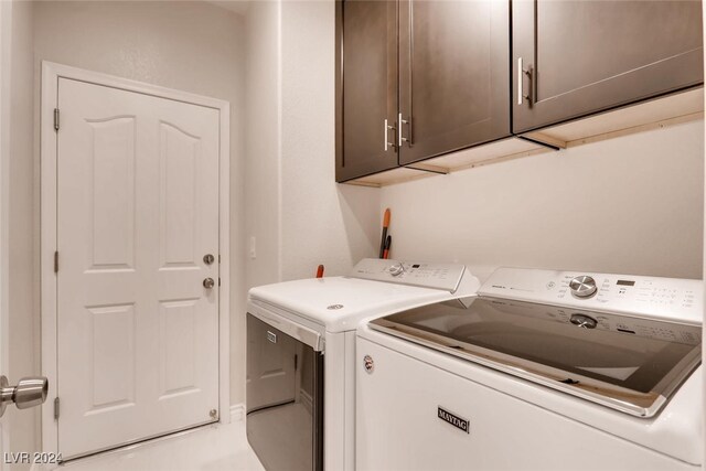 clothes washing area with separate washer and dryer and cabinets