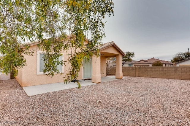 back of property featuring a tile roof, a patio area, fence, and stucco siding