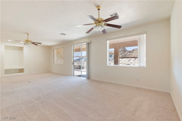 empty room with a textured ceiling, ceiling fan, and light colored carpet