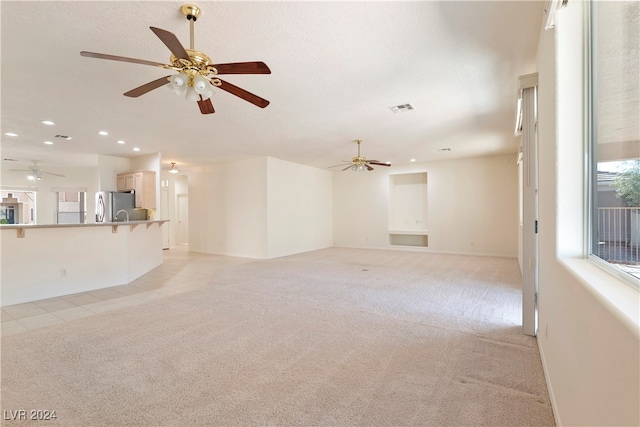 unfurnished living room with ceiling fan and light carpet