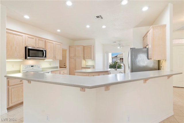 kitchen featuring appliances with stainless steel finishes, light brown cabinets, light tile patterned floors, and kitchen peninsula