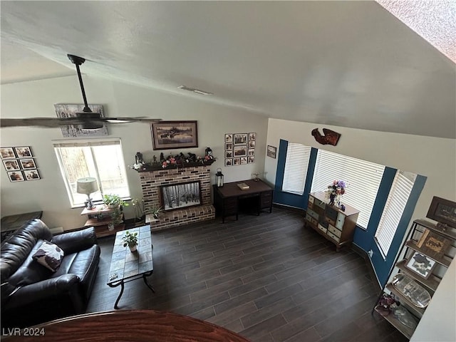 living area featuring a ceiling fan, visible vents, vaulted ceiling, dark wood-type flooring, and a brick fireplace