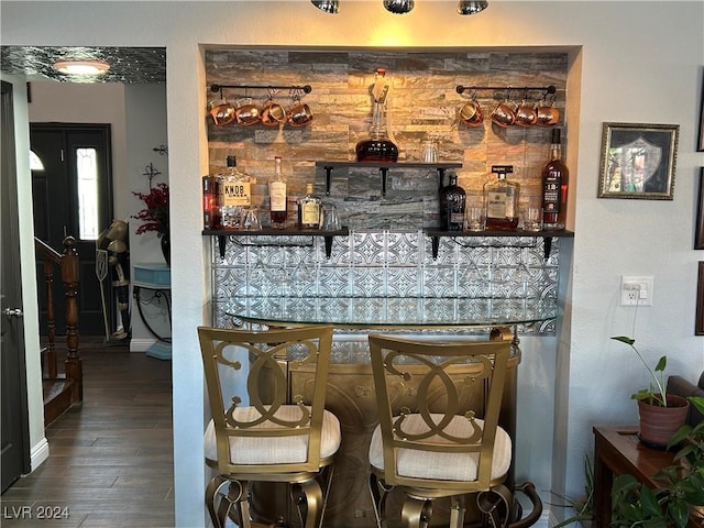 bar featuring a bar, baseboards, and wood finished floors