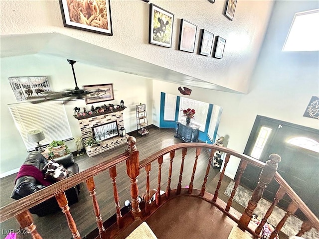 stairway with a ceiling fan, a high ceiling, a fireplace, and baseboards