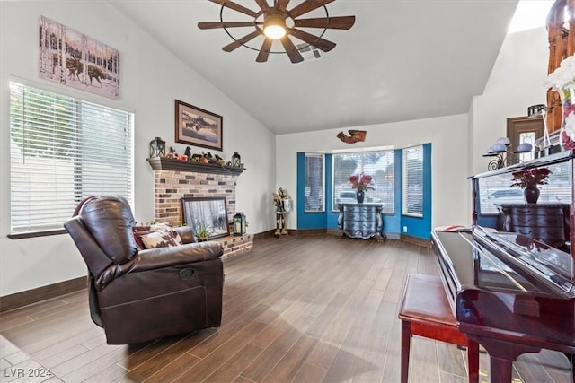 living area with a ceiling fan, a brick fireplace, wood finished floors, and high vaulted ceiling