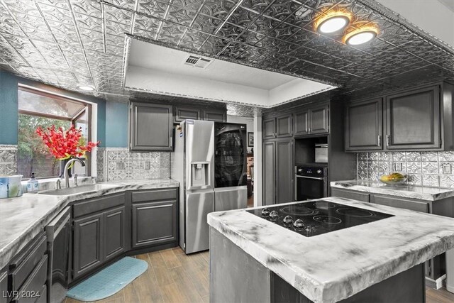 kitchen featuring visible vents, light wood-type flooring, black appliances, a sink, and an ornate ceiling