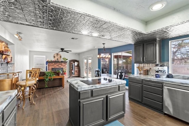 kitchen with a brick fireplace, black electric stovetop, light countertops, and dark wood-type flooring