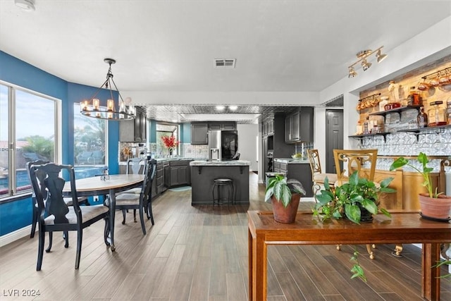 dining space with a wealth of natural light, visible vents, an inviting chandelier, and wood finished floors