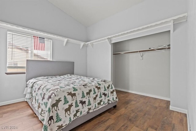 bedroom featuring vaulted ceiling, wood finished floors, a closet, and baseboards