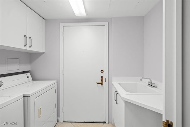 clothes washing area with light tile patterned floors, washing machine and dryer, cabinets, and sink