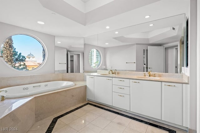 bathroom featuring tile patterned floors, a tray ceiling, tiled tub, and vanity