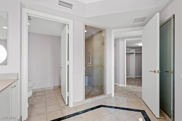 bathroom featuring vanity, toilet, tile patterned floors, and a shower with door