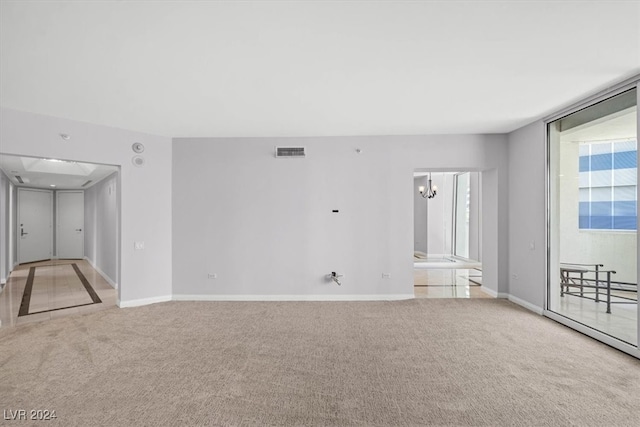 carpeted empty room featuring an inviting chandelier