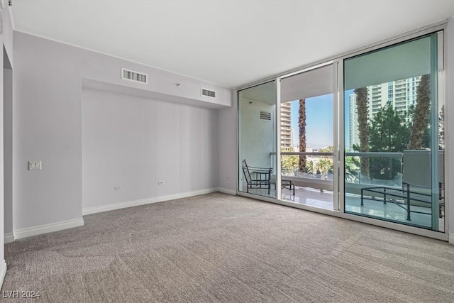 carpeted spare room featuring a wall of windows