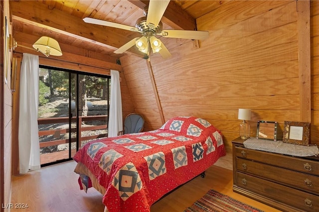 bedroom with lofted ceiling with beams, a ceiling fan, wooden walls, wood finished floors, and wooden ceiling