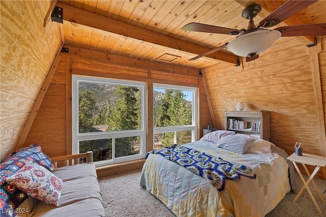 carpeted bedroom featuring ceiling fan, wooden walls, beam ceiling, and multiple windows