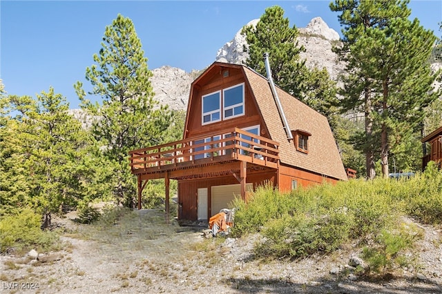 rear view of property featuring a garage and a deck with mountain view