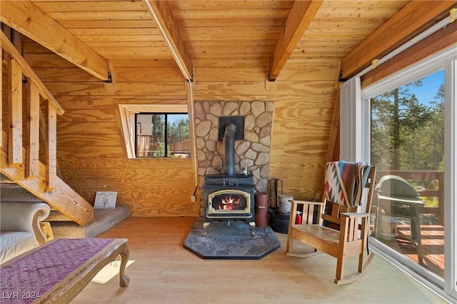 living area with wooden ceiling, wood finished floors, a wood stove, vaulted ceiling with beams, and wood walls