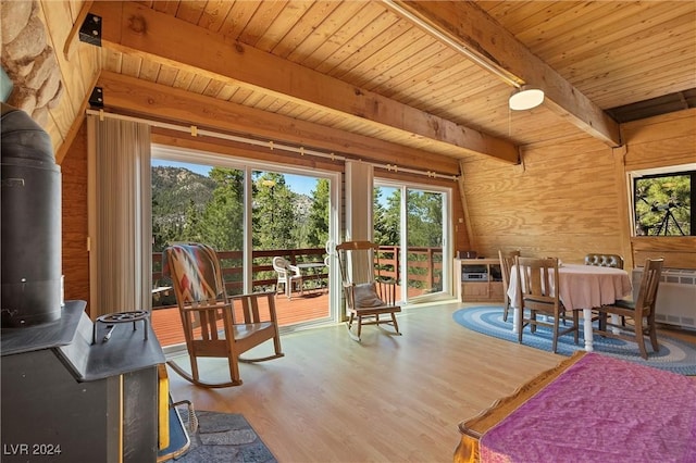 sunroom with a wood stove, a healthy amount of sunlight, and wood ceiling