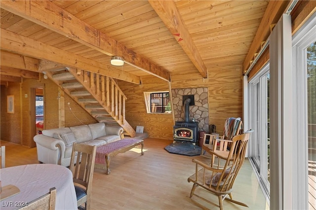 living room with a wood stove, wooden ceiling, beamed ceiling, and wood walls