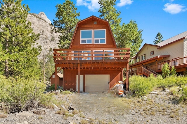 rear view of house featuring a wooden deck and a garage