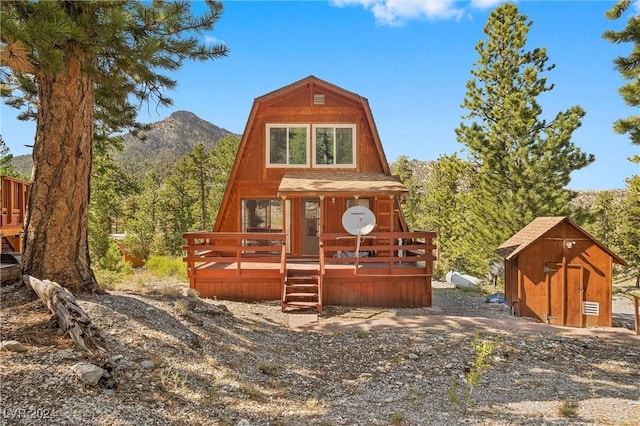 view of front of home with a deck with mountain view, a storage unit, and an outdoor structure