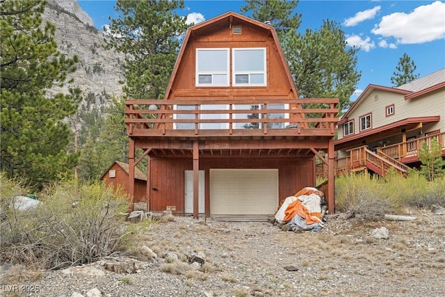 back of house with a garage, driveway, and a deck
