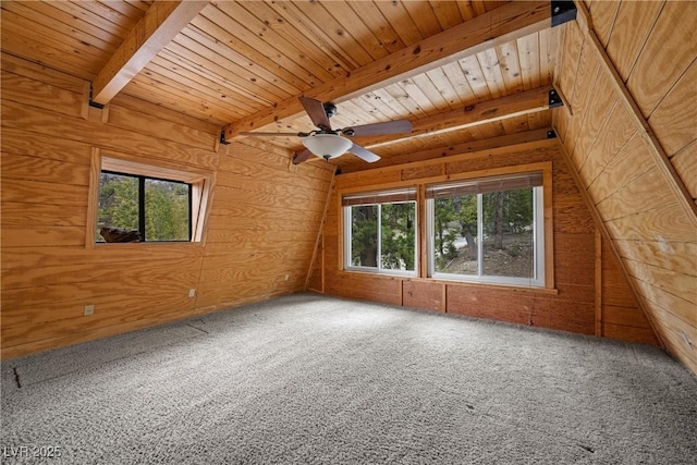 carpeted spare room featuring wood walls, ceiling fan, wooden ceiling, and beamed ceiling