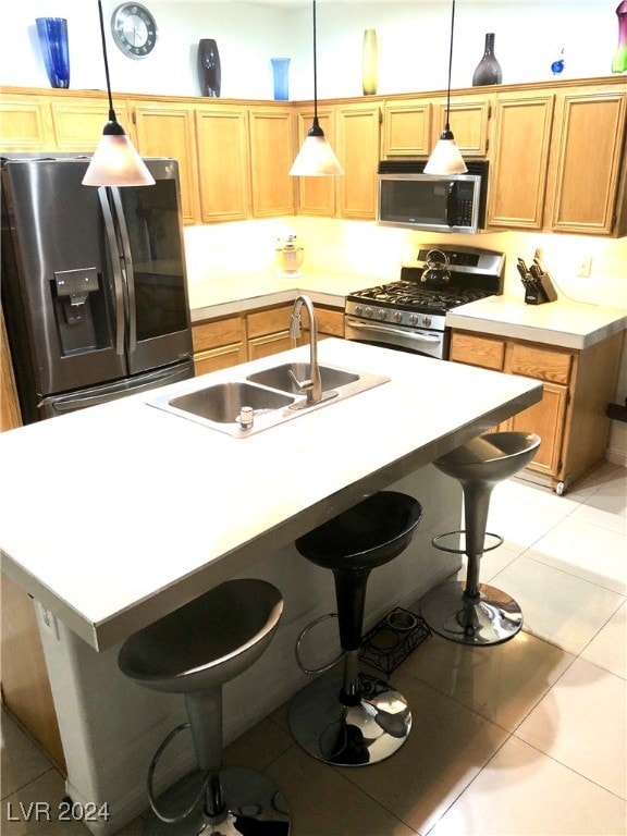 kitchen with light tile patterned flooring, stainless steel appliances, hanging light fixtures, and an island with sink