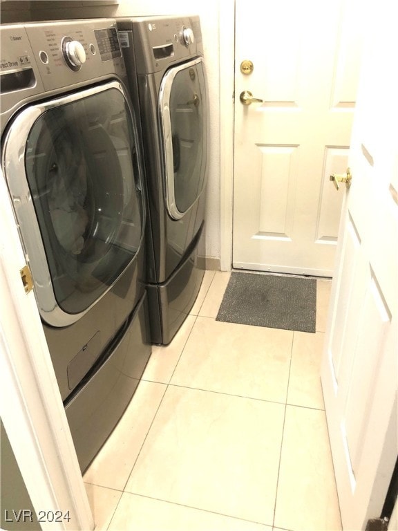 clothes washing area with washing machine and dryer and light tile patterned floors