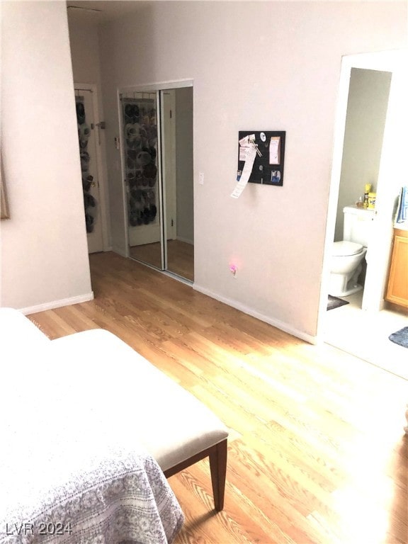 bedroom with ensuite bath and light wood-type flooring