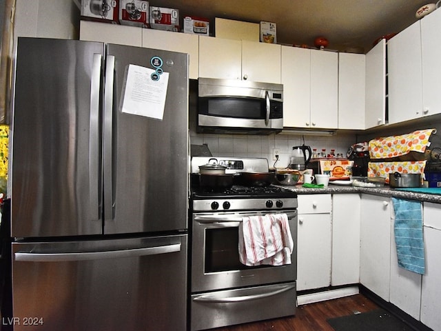 kitchen with appliances with stainless steel finishes, decorative backsplash, dark wood-type flooring, and white cabinetry