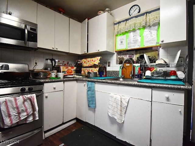 kitchen featuring appliances with stainless steel finishes, dark hardwood / wood-style floors, decorative backsplash, and white cabinets