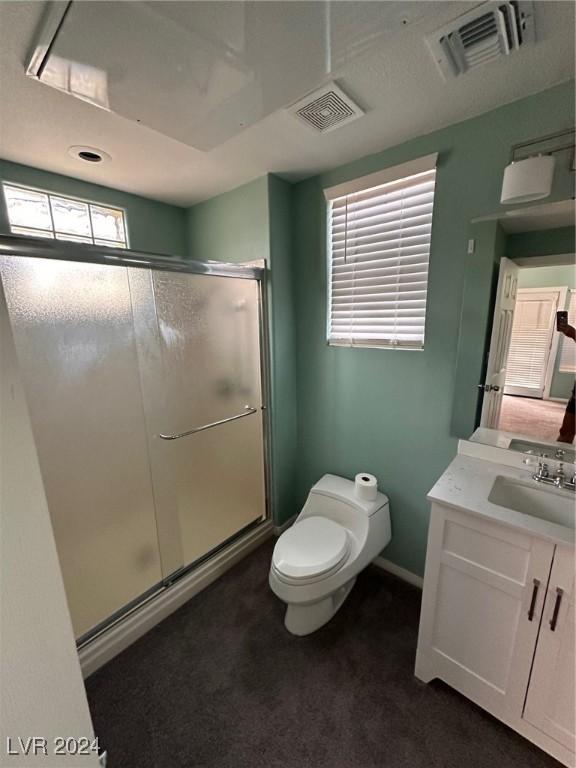 bathroom with toilet, a shower with shower door, and vanity