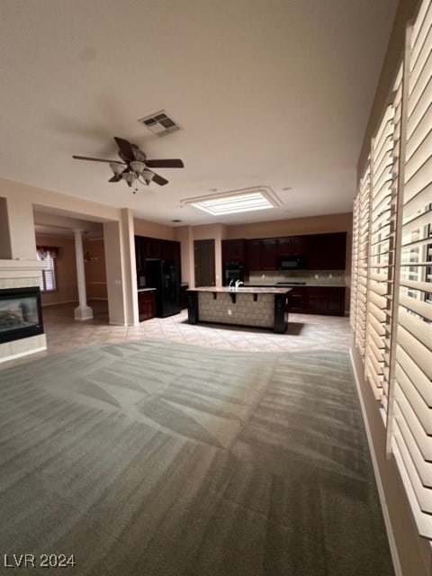 interior space featuring light colored carpet, ornate columns, and ceiling fan