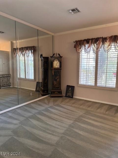 unfurnished living room with carpet, plenty of natural light, and ornamental molding