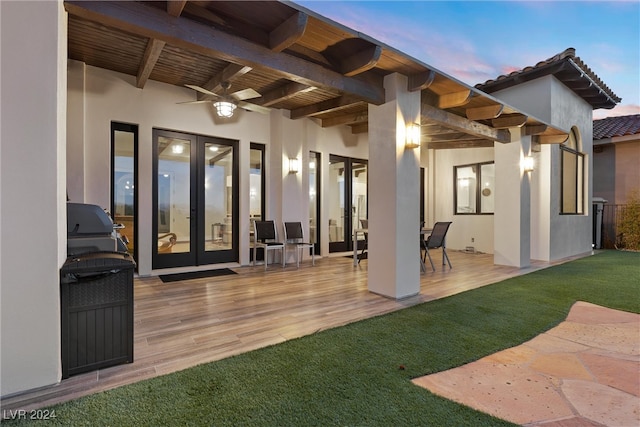 patio terrace at dusk with a wooden deck, ceiling fan, and french doors