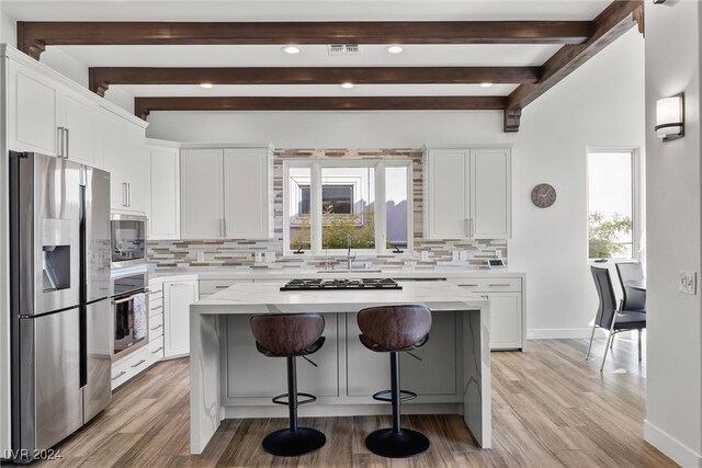 kitchen with appliances with stainless steel finishes, a healthy amount of sunlight, light wood-type flooring, and white cabinets