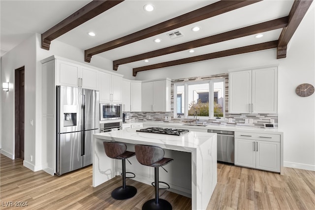 kitchen featuring a kitchen island, stainless steel appliances, decorative backsplash, and light hardwood / wood-style flooring