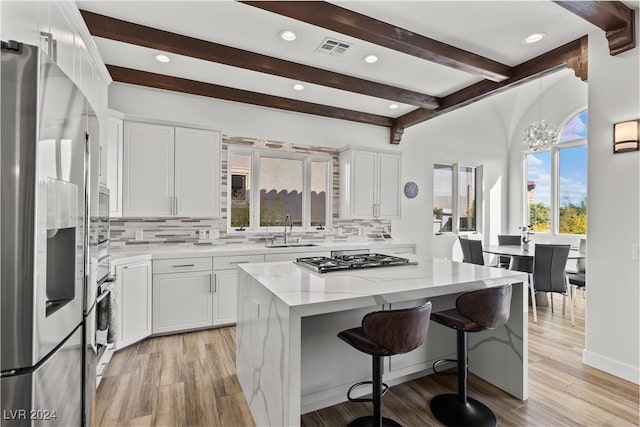 kitchen featuring light wood-type flooring, appliances with stainless steel finishes, sink, and decorative backsplash