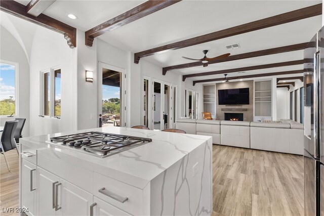 kitchen with white cabinetry, light wood-type flooring, light stone counters, stainless steel gas cooktop, and ceiling fan