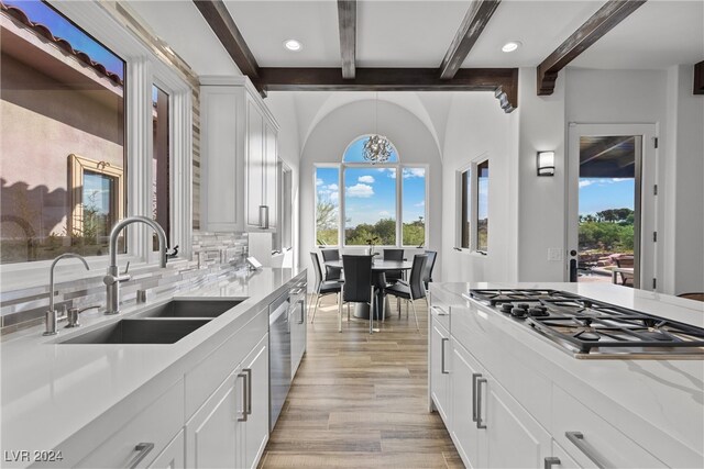 kitchen featuring appliances with stainless steel finishes, light hardwood / wood-style flooring, decorative backsplash, sink, and white cabinets