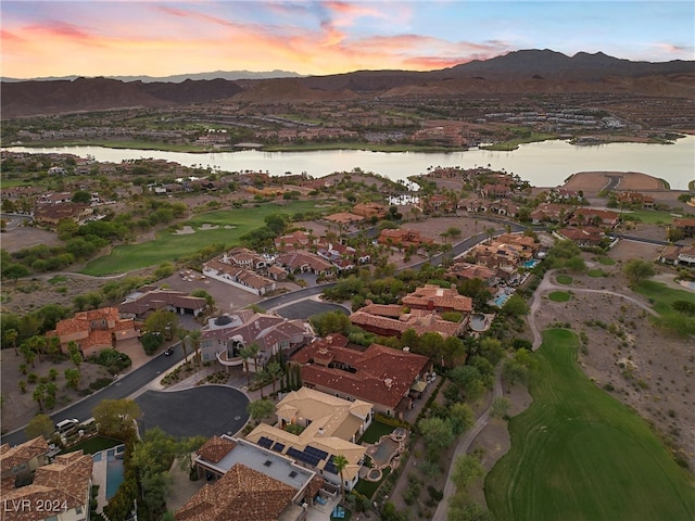 aerial view at dusk featuring a water and mountain view